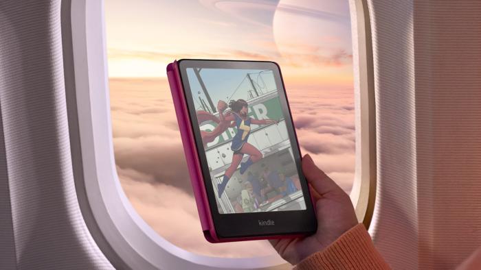 A hand holding a tablet with a color display against the window of an airplane.