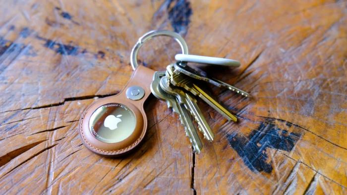 An AirTag in a leather keychain case attached to a ring with several keys