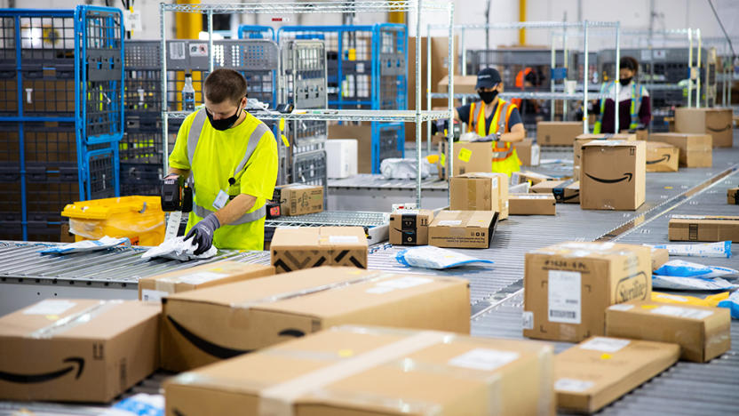 An Amazon warehouse with workers boxing and taping with conveyor belts surrounding them.