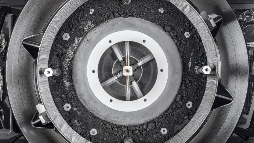 A top-down look into the sample container showing dark dust and rocks taken from asteroid Bennu