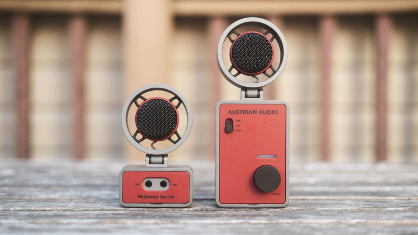 The Austrian Audio MiCreator in two parts: Two round microphones sit atop one smaller and one larger rectangular bases facing the camera and seen on a weathered wooden outdoor table.