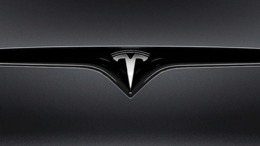 Closeup of a Tesla logo on a car.