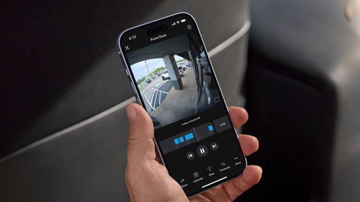 Image of a smartphone showing the Ring app with a 24/7 video feed on its display.