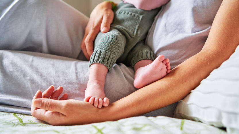 Cropped photo of an unrecognizable baby eating from mother's breast while lying in bed