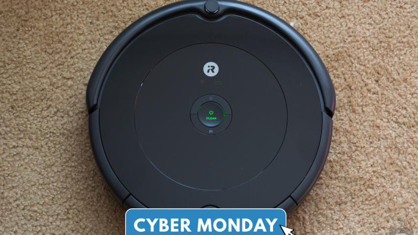 A Roomba robot vacuum sits on a carpet under a Cyber Monday logo. 