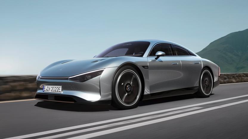 A silver Mercedes-Benz VISION EQXX concept car rides along a cliffside highway with a hill in the distance on the right.